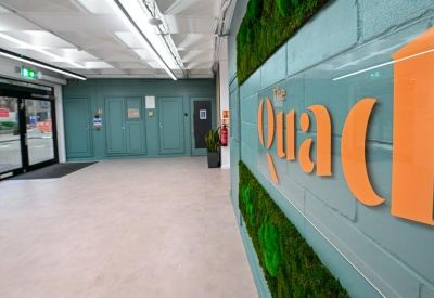 Reception area featuring a branded green moss wall with orange lettering.