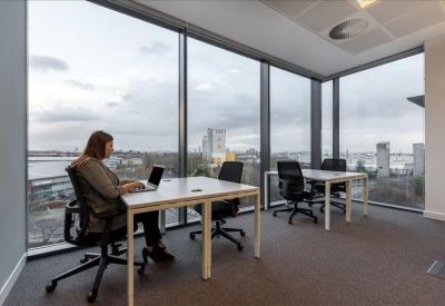 Corner office with two white desks and large windows overlooking the city.