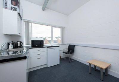 Communal kitchenette with white cabinetry and a small dining table.