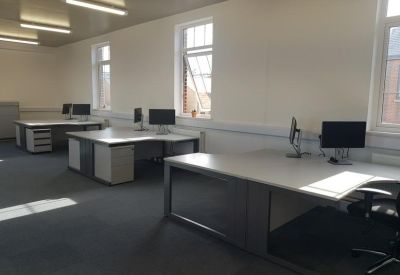 Spacious open-plan office featuring multiple L-shaped desks and natural light.