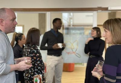 People networking in a bright communal area with coffee.