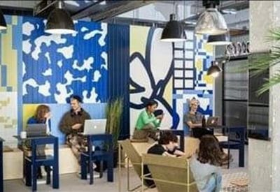 Vibrant coworking space with a blue and white patterned feature wall and laptop stations.