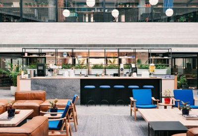 Modern lounge area with leather sofas, blue armchairs, and a stylish coffee bar.