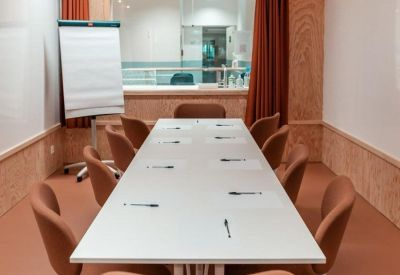 Professional meeting room featuring a long white table and modern brown chairs.
