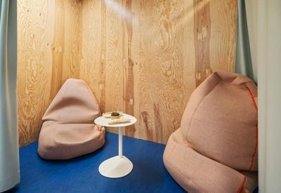 Small breakout room with two pink bean bags and a round white table against plywood walls.