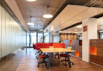 Vibrant coworking area featuring warm wood floors and bright orange desk dividers.