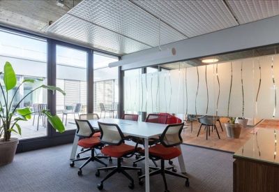 Sunlit meeting area with grey chairs and a view of an outdoor patio.