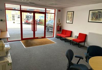 Reception lobby area showing the glass front entrance doors and red visitor seating.