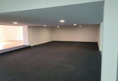 Low-ceilinged internal storage or studio space with dark grey carpeting and recessed lighting.