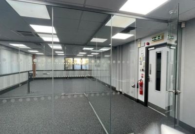 Open-plan office with glass partitions and modern recessed ceiling lighting.