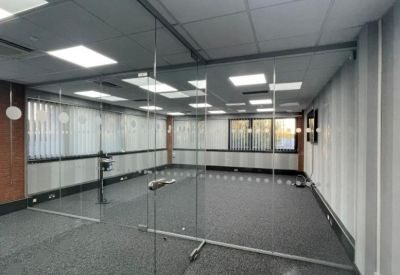 Bright glass-walled meeting room with grey carpeting and large windows.
