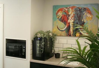 Kitchenette area with a vibrant elephant painting and a built-in microwave.