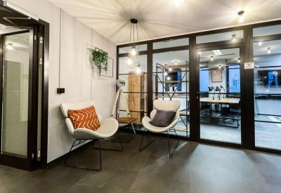 Modern reception lobby with white bucket chairs, orange cushions, and glass partition walls.