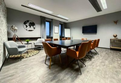 Spacious boardroom featuring a large black table, orange leather chairs, and a world map wall decal.