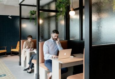 Private glass-partitioned workspaces with integrated greenery and individual desks.