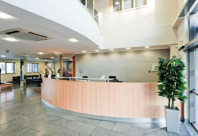 Modern curved wooden reception desk in a bright, high-ceilinged lobby.