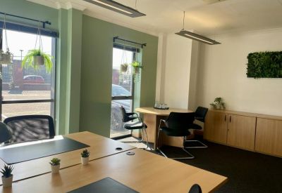 Bright private office with green feature wall and potted plants.