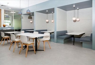 Bright breakout area with cafe-style seating and private cushioned booths.