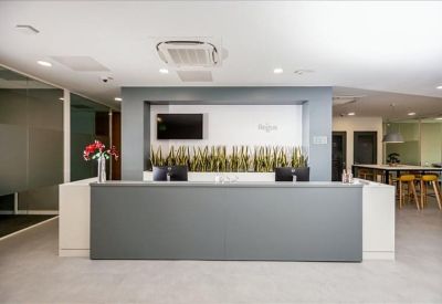 Sleek reception desk in grey and white with minimalist wall decor and indoor plants.