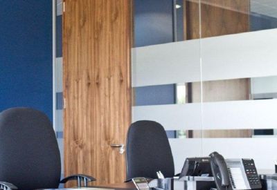 Bright office workspace with wooden desks and ergonomic black chairs.
