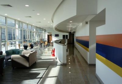 Bright glass-walled lounge area with comfortable seating and colourful wall stripes.