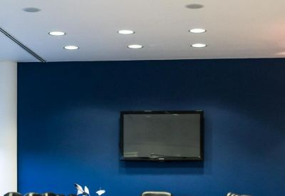 Boardroom featuring a long wooden table, black leather chairs, and a blue accent wall.