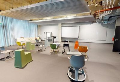 Spacious communal workshop area with colorful chairs and a large projector screen.