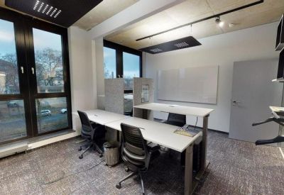 Small private office suite with two desks and a large window providing natural light.