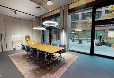 Formal boardroom with a long wooden table, blue chairs, and a large window overlooking a courtyard.