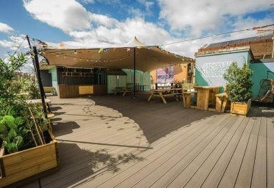 Outdoor roof terrace with wooden decking, picnic tables, and a large canopy tent.