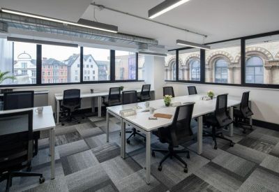 Bright office suite with white desks, ergonomic mesh chairs, and large city-view windows.