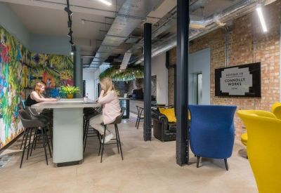 Breakout space with blue and yellow armchairs, breakfast bar, and industrial lighting.