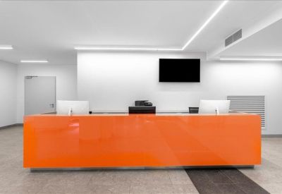 Bright reception area featuring a vibrant orange front desk and minimalist white walls.