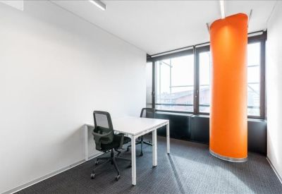 Private glass-walled office with a white desk and a bold orange acoustic privacy pillar.