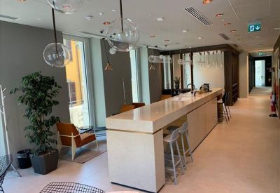 Long white breakfast bar with stools and glass pendant lights in a contemporary common area.