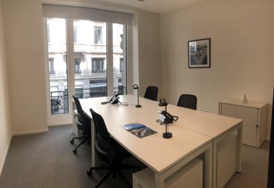 Efficient four-person workspace with white desks and natural light from large windows.