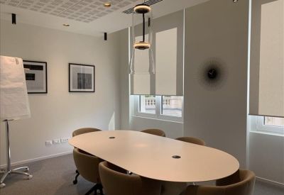 Meeting room with oval white table and two framed abstract artworks.