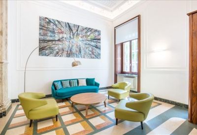 Stylish lounge area with a teal curved sofa, green armchairs, and abstract wall art.