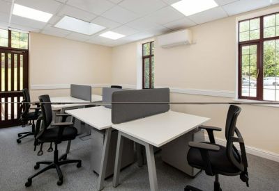 Bright open-plan office space with multiple white desks and grey privacy dividers.