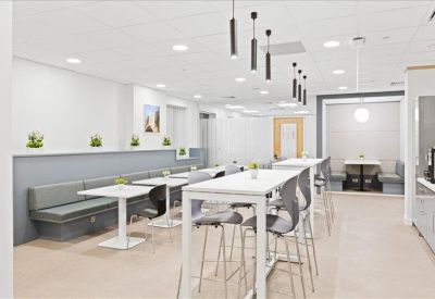 Spacious coworking lounge and dining area with booth seating and high tables.