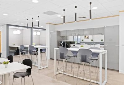 Contemporary office kitchen and break area with high-top seating and coffee facilities.