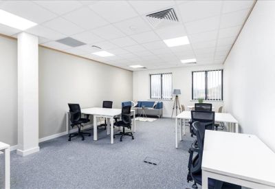 Bright open-plan office space with white desks and ergonomic black chairs.