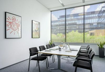 Sleek meeting room featuring a white table, black chairs, and a large window overlooking the city.