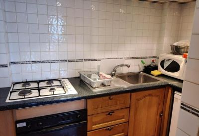 Kitchenette area with a gas stove, tiled backsplash, and wooden cabinets.