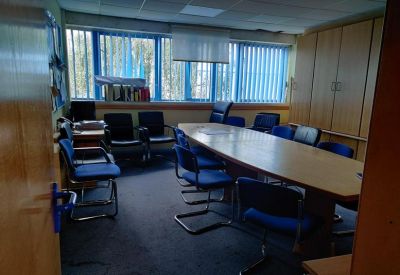 Meeting room with a large oval table and blue chairs.