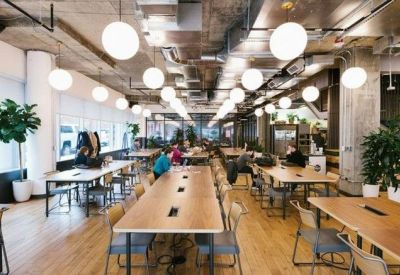 Spacious coworking area at Dalton Place with long wooden tables and hanging globe lights.