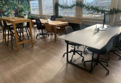 Bright coworking area with wooden tables, black chairs, and floral wallpaper.