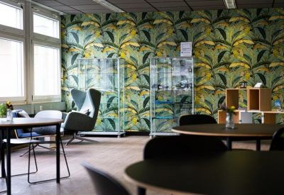 Meeting area featuring a round table and modern chairs against tropical leaf wallpaper.