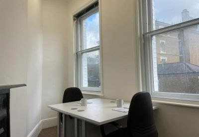 Meeting room with two black chairs, a white table, and large windows overlooking the city.