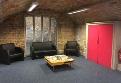 Breakout area with black leather sofas and a bright pink accent storage cabinet.